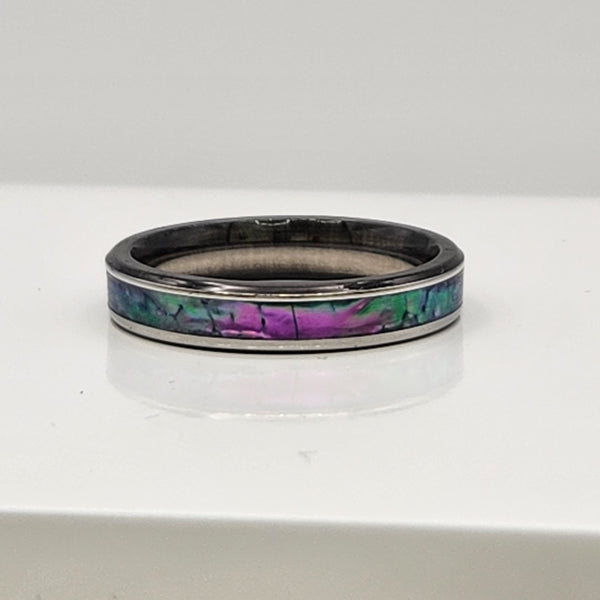 Hand-turned dichroic resin ring on a stainless steel band, shifting purple, blue, and green in the light.