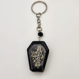 Coffin shaker keychain filled with oil and floating charms.