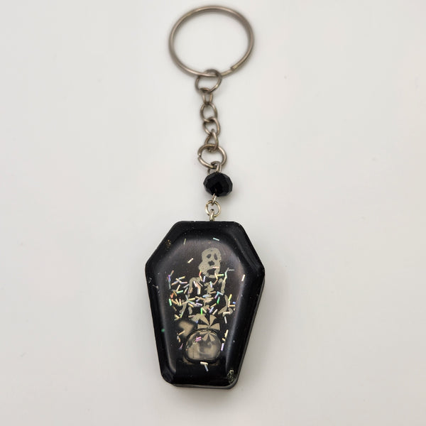 Coffin shaker keychain filled with oil and floating charms.
