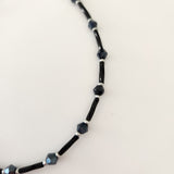 Black beaded anklet with silver accents and a chain attachment.