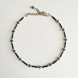 Adjustable black ankle bracelet with multicolored beads and a metallic clasp.