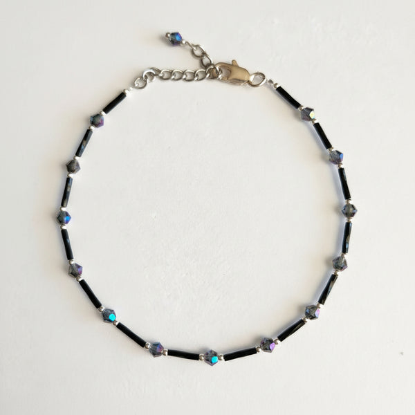 Adjustable black ankle bracelet with multicolored beads and a metallic clasp.