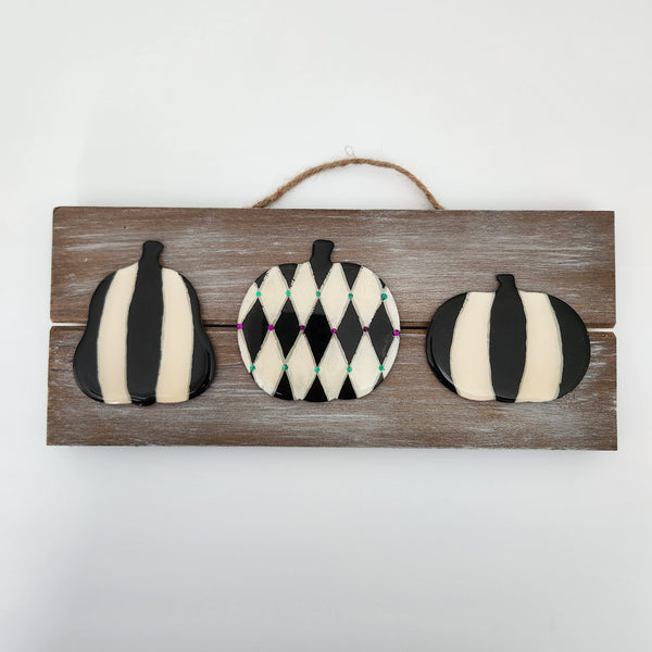 A hand-painted pumpkin sign coated in resin, displayed on a wooden board with a hanger.