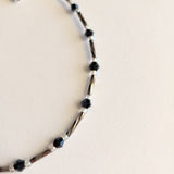 Adjustable blue and gunmetal anklet with a chain.