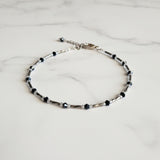 Adjustable blue and gunmetal anklet with a chain.