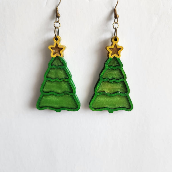 A pair of green Christmas tree-shaped earrings with yellow stars on top, made of wood and resin, with brass hooks.