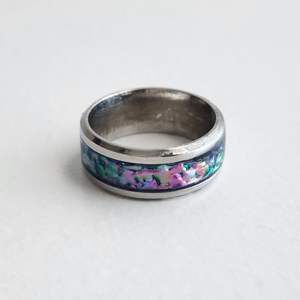 Hand-turned dichroic resin ring on a stainless steel band, shifting purple, blue, and green in the light.