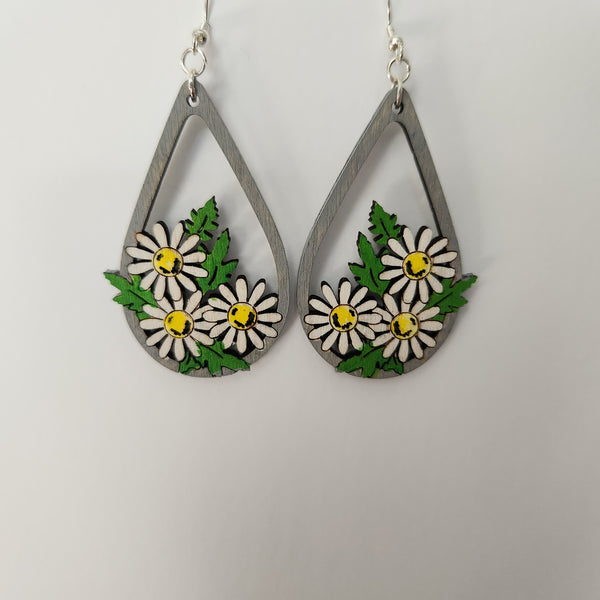 A pair of silver hook earrings with daisy designs in green, yellow, white, and gray colors.