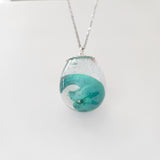 Resin dinosaur encased in clear egg pendant on stainless steel chain
