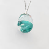 Resin dinosaur encased in clear egg pendant on stainless steel chain