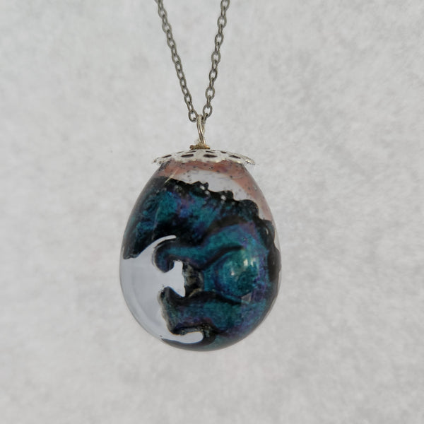Resin dinosaur encased in clear egg pendant on stainless steel chain