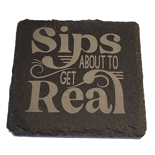 A black slate coaster with the engraved phrase 'SIPS ABOUT TO GET REAL'.
