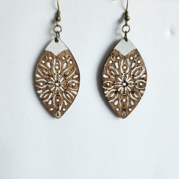 A pair of hand painted wood earrings with brass hooks, featuring a geometric floral pattern.