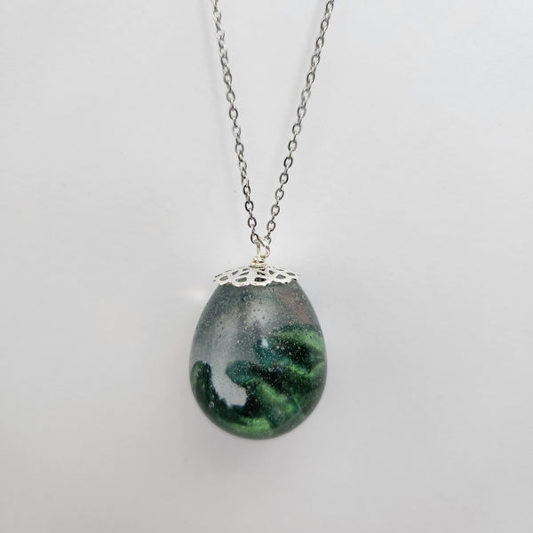 A green long neck dino egg-shaped pendant on a stainless steel chain.