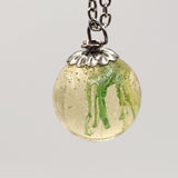 Suspended ink resin pendant on silver stainless steel chain.