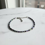 An adjustable ankle bracelet with multicolored beads and a chain.