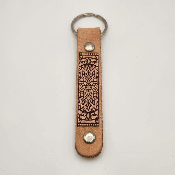Laser-engraved leather key fob keychain with detailed design.