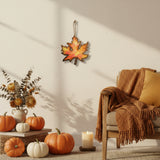 Handmade wooden maple leaf filled with resin in fall colors by Blue Bourbon Designs shown being displayed on a wall