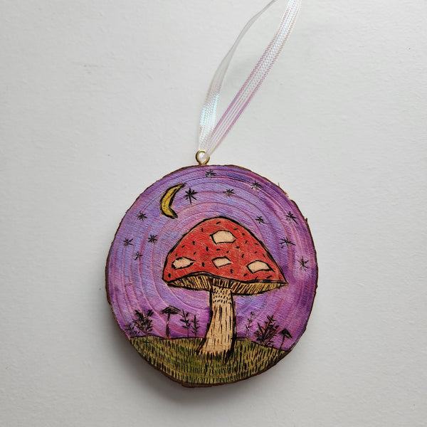 Hand burned and painted mushroom design on a wood slice, with a hanger at the top.