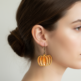 Woman wearing a pumpkin-shaped earring on a plain background