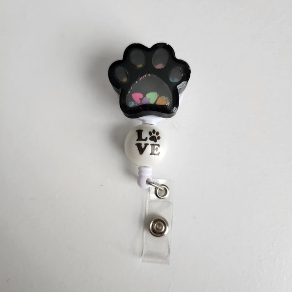 Handmade paw print shaker badge reel with moving clay shapes by Blue Bourbon Designs.