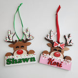 Hand painted wooden reindeer ornaments with red and green details, customized with name of your choice hanging from green and red ribbons.