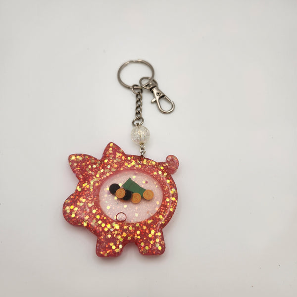 Piggybank shaker keychain filled with oil and floating charms.