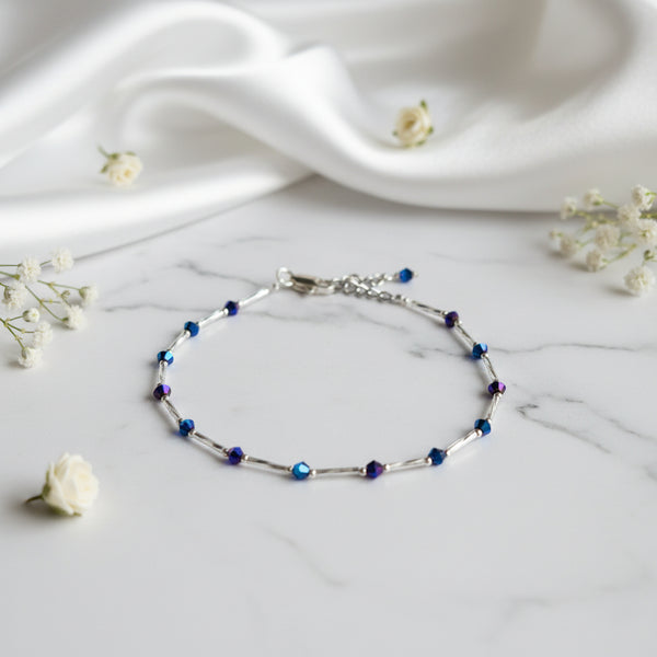 An adjustable anklet with a chain link design and purple and blue beads.