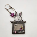 Rabbit in a hat shaker keychain filled with oil and moving charms.