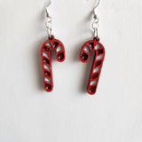 A pair of red and white striped candy cane earrings with silver hooks.