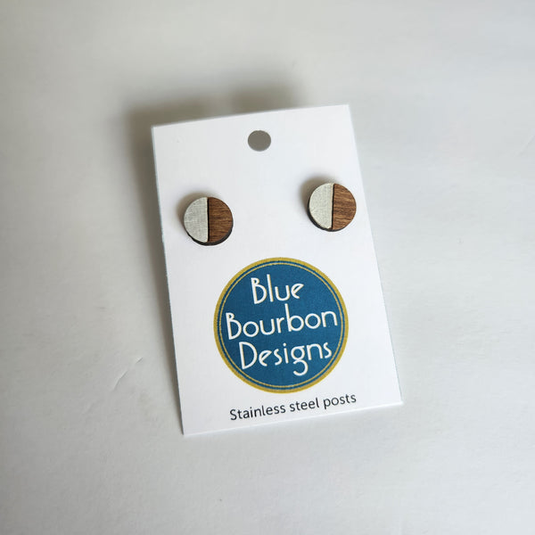 A pair of round white and wood stud earrings on a stainless steel post, packaged on a card with 'Blue Bourbon Designs' branding.