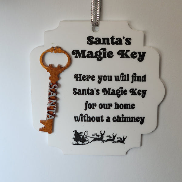 Acrylic and resin ornament in the shape of a key with the text 'Santa's Magic Key' and a message 'Here you will find Santa's Magic Key for our home without a chimney' on a white background.