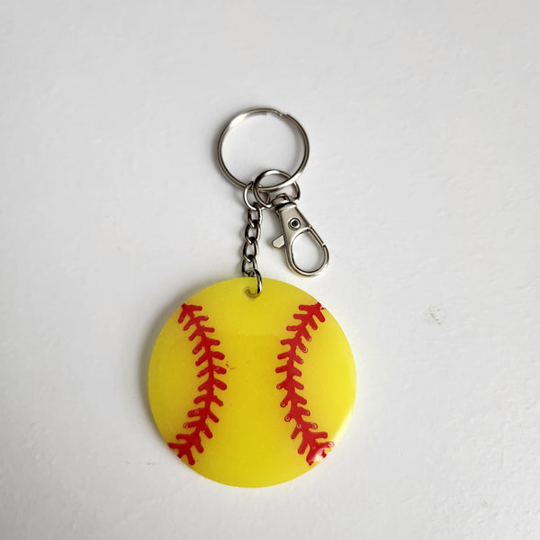Yellow softball resin keychain with red stitching details