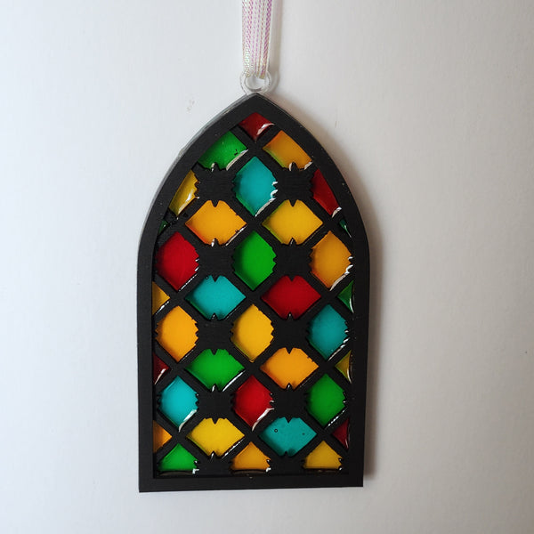 A resin window ornament designed to look like stained glass with a geometric pattern in multiple colors.