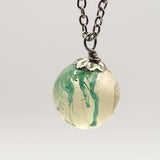 Suspended ink resin pendant on silver stainless steel chain.