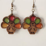 A pair of wood and resin earrings shaped like a turkey, with brass hooks.