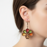 Close-up of a person wearing a colorful earring with a turkey design on a plain background