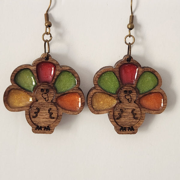 A pair of wood and resin earrings shaped like a turkey, with brass hooks.