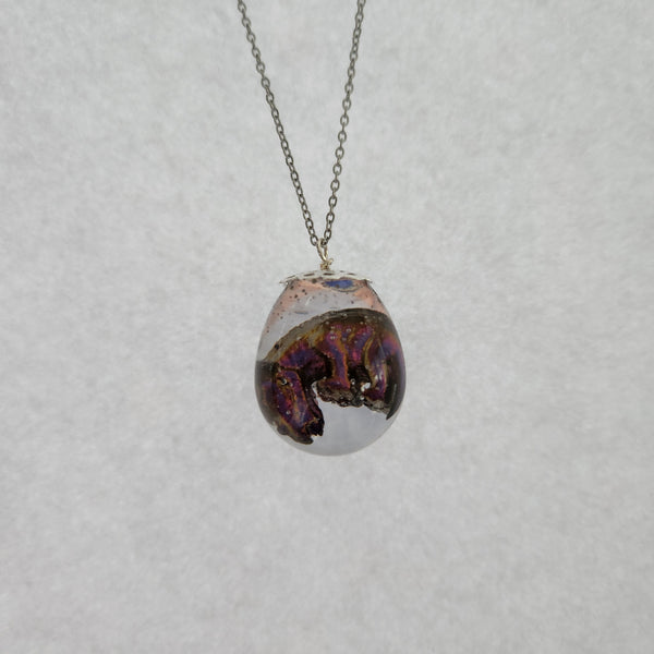 A triceratops egg-shaped pendant on a stainless steel chain.