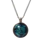 A domed resin circle necklace with a green and blue iridescent design on a silver stainless steel chain.