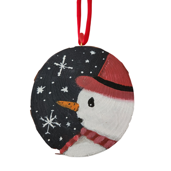 Hand painted wood slice ornament featuring a snowman with a red hat and scarf with a navy background with snowflakes.