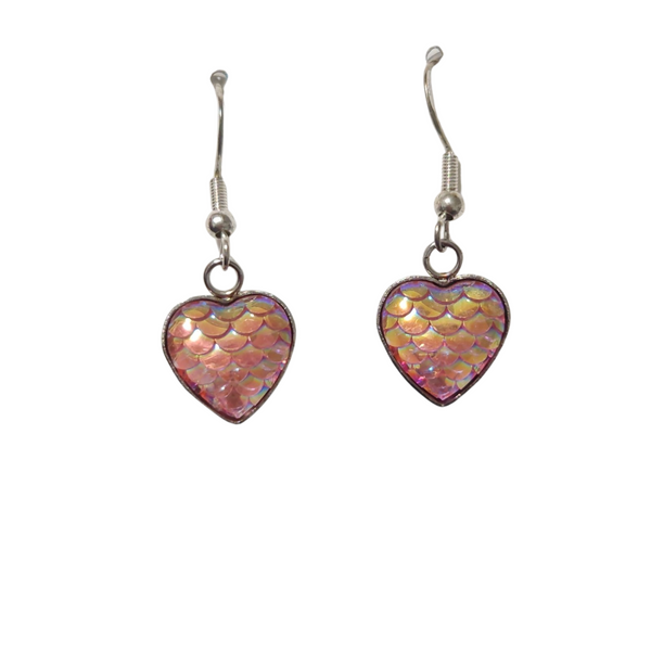 A pair of light pink, heart-shaped dangle earrings with a mermaid scale pattern, suspended on silver stainless steel hooks.