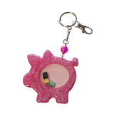 Piggybank shaker keychain filled with oil and floating charms.